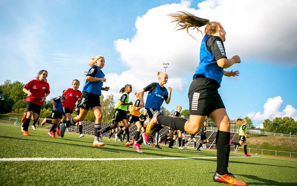Unga kvinnor som tränar fotboll på en konstgräsplan.